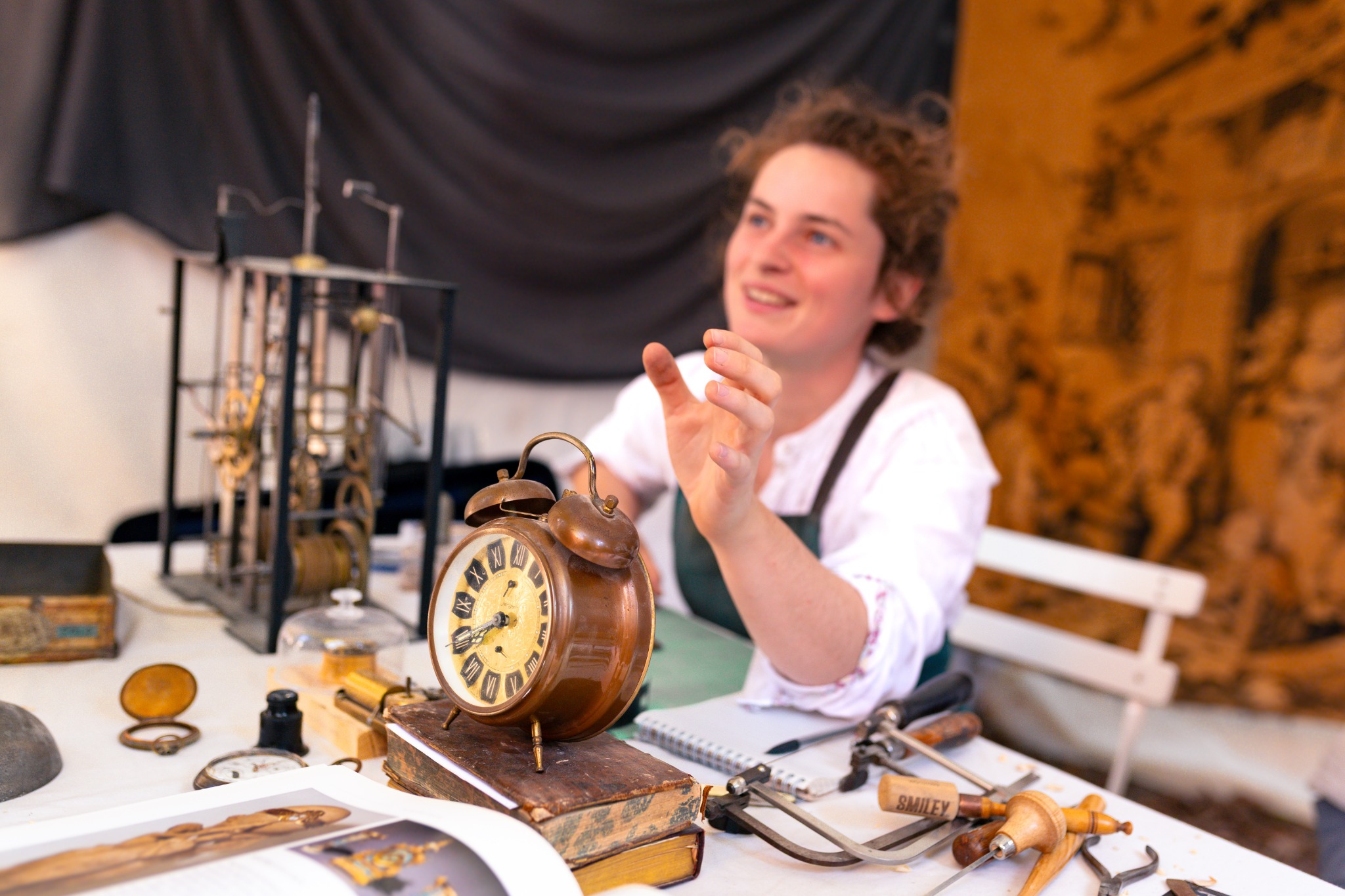 Horlogère présentant un réveil ancien dans son atelier